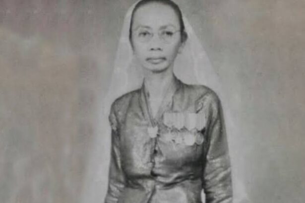 Black-and-white portrait of a woman wearing a veil and a medal-decorated dress, facing the camera.
