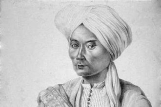 Portrait of a man in a turban and traditional robe, with a ceremonial sword across his chest.
