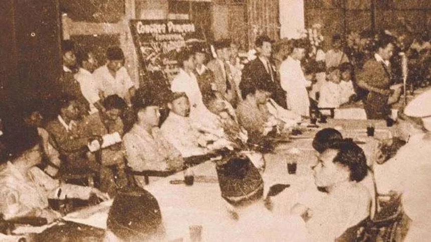 Crowded formal meeting with many people seated around a long table in a sepia-toned vintage photograph.