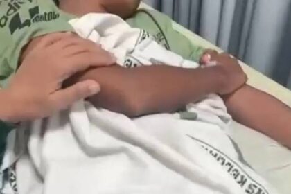 Parent gently holding a newborn wrapped in a white blanket in a hospital bed.