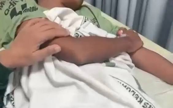 Parent gently holding a newborn wrapped in a white blanket in a hospital bed.