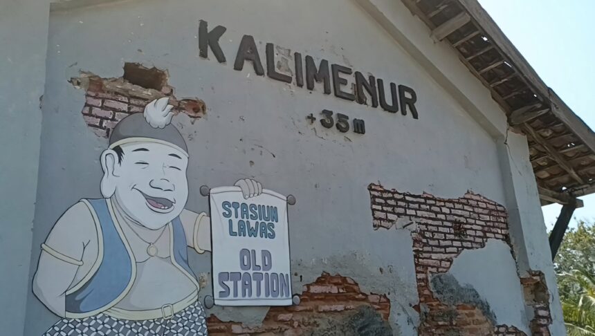 Cartoon man in overalls and cap smiling, holding a sign that reads 'Stasiun Lama' on a weathered wall with exposed bricks.
