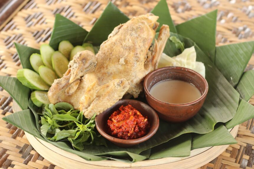 Fried fish on banana leaves with lime slices, served with chili sauce and dipping sauce.