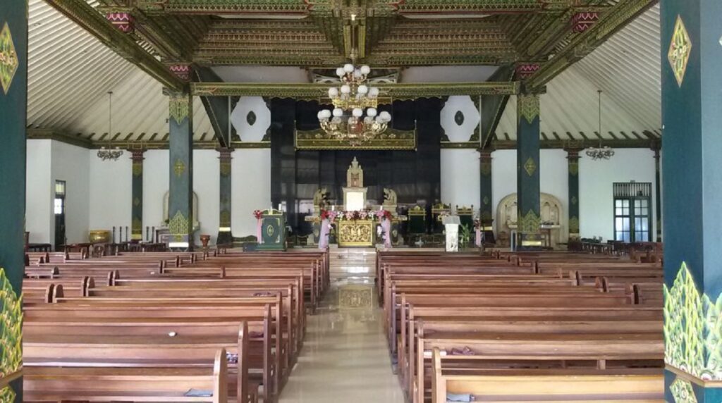 Interior of a church or temple with wooden pews, ornate columns, and a gilded altar at the front.