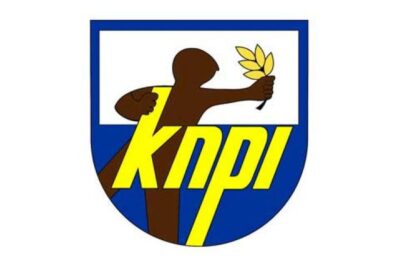 KDPI logo: blue shield with a brown figure offering an olive branch and bold yellow 'KDPI' lettering