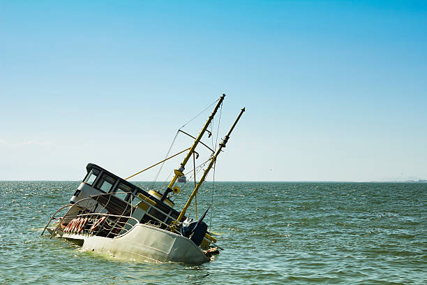 Sunken boat partially submerged in calm blue-green water near the horizon, tilted to one side.