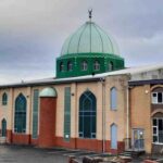 Brick building with a prominent green dome and tall arched windows, suggesting a religious or cultural center.