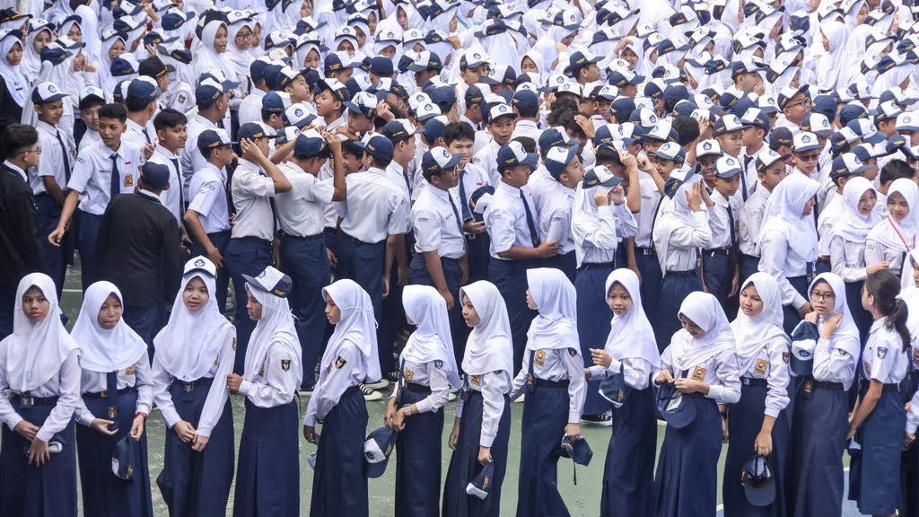 Large group of students in white shirts and navy uniforms standing in rows for a school assembly outside.