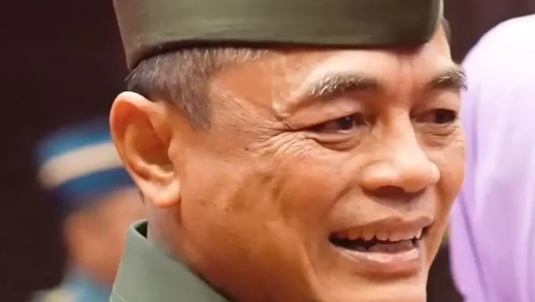 Close-up of a smiling man in a green cap, facing slightly to the right, expression warm and cheerful.