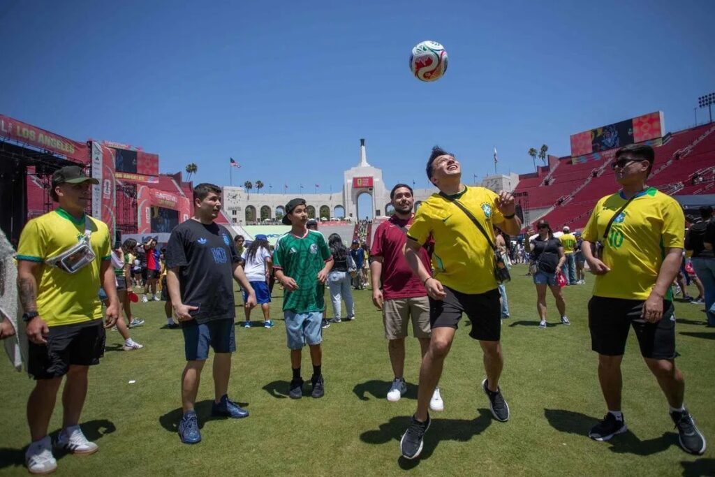 juggling bola di fan fest by the strait times - Mabur.co People playing soccer on a sunny field as a man in a yellow jersey leaps to head the ball while others watch.