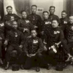 Group of military officers in dress uniforms with medals posing for a formal studio portrait.