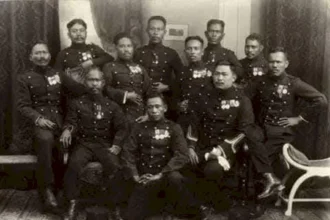 Group of military officers in dress uniforms with medals posing for a formal studio portrait.