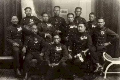 Group of military officers in dress uniforms with medals posing for a formal studio portrait.