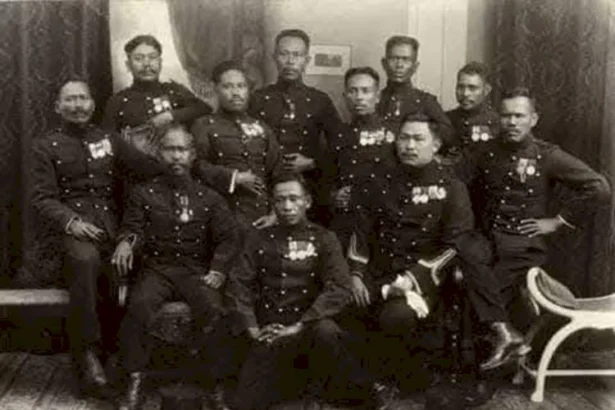 Group of military officers in dress uniforms with medals posing for a formal studio portrait.