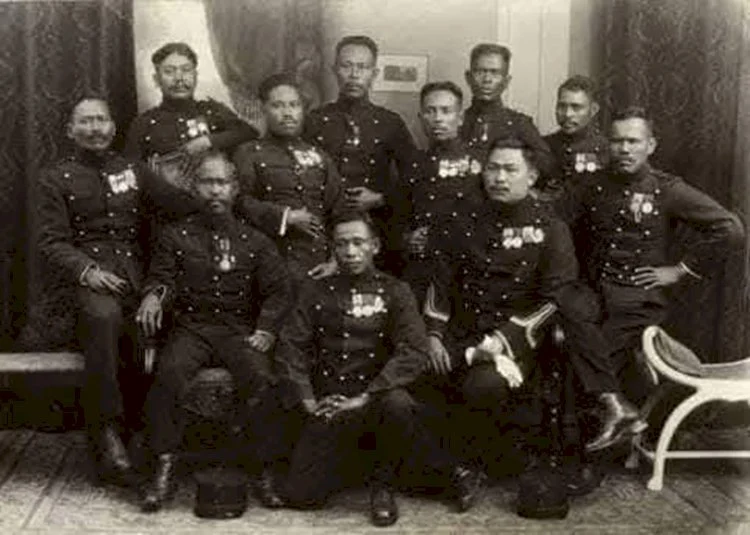 Group of military officers in dress uniforms with medals posing for a formal studio portrait.