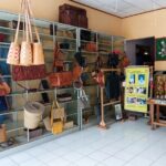 Boutique display of leather handbags and purses on metal shelves in a sunny shop interior