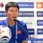 Asian man in a blue shirt speaks at a press conference with a soccer ball on the table and sponsor logos in the background, including Hyundai and Shopee.