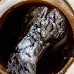 Mug of black coffee with a burnt, crumpled object floating in the liquid