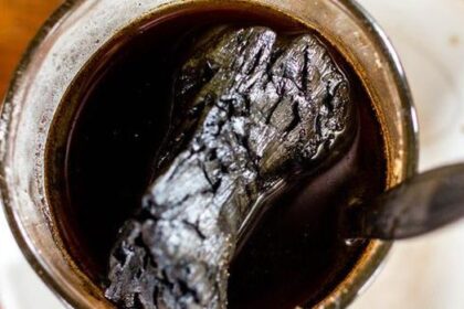 Mug of black coffee with a burnt, crumpled object floating in the liquid