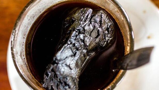 Mug of black coffee with a burnt, crumpled object floating in the liquid