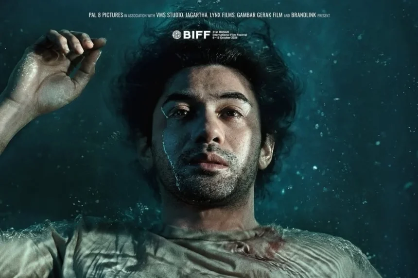 Man underwater, floating on his back with one hand above his head, moody lighting and bubbles around.