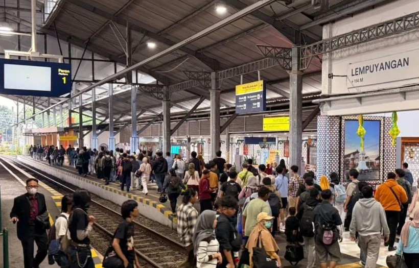 Crowded train platform at Lempuyangan station with many passengers waiting along the tracks, signs overhead.