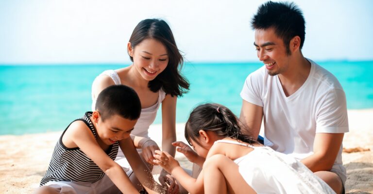 Family of four at the beach, kneeling in the sand and playing with sand near the turquoise sea, smiling and engaging together.