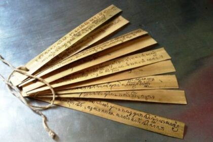 Wooden folding fan with handwritten text on each slat, tied together at the base with string.