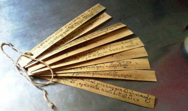 Wooden folding fan with handwritten text on each slat, tied together at the base with string.