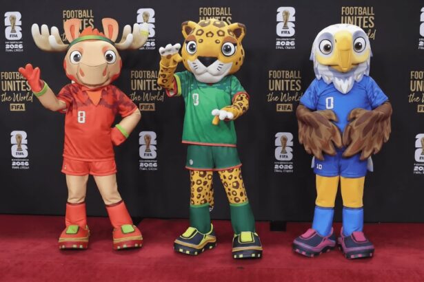 Three colorful sports mascots posing on a red carpet in front of a black backdrop with 'Football Unites the World' branding.