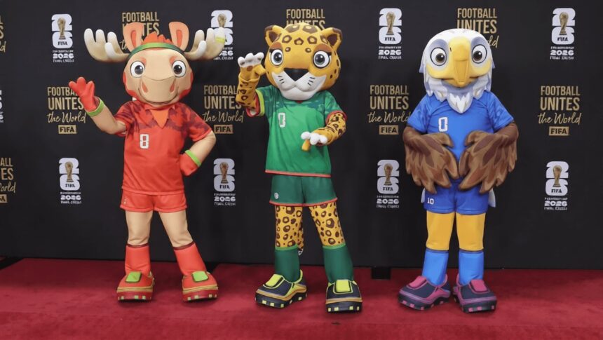 Three colorful sports mascots posing on a red carpet in front of a black backdrop with 'Football Unites the World' branding.