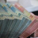 A close-up of colorful stacked banknotes fanned out in rows, showing multiple denominations and colors (e.g., euros).