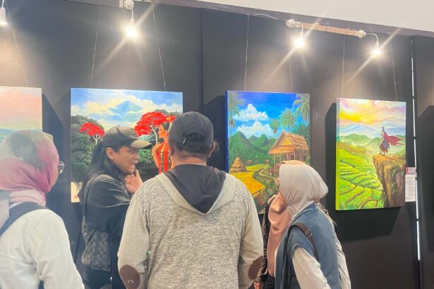 People in an art gallery viewing colorful landscape paintings on black walls.