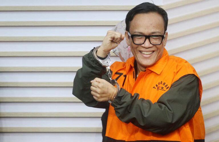 noel-minta-amnesti-saut-ada-prosedurnya-24082025-111715 - Mabur.co Smiling man in orange inmate uniform displaying handcuffs in his raised hand