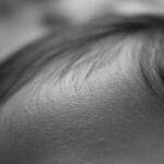 Extreme close-up of a closed eye, with eyelashes resting along the eyelid in grayscale.