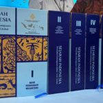Set of Indonesian history books on a blue display table, blue covers with 'Sejarah Indonesia' and volumes I–V, plus a QR code card on the right, and gold decorative panels behind them.