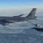 Air Force KC-135 Stratotanker refueling a fighter jet in mid-air over a snowy landscape.
