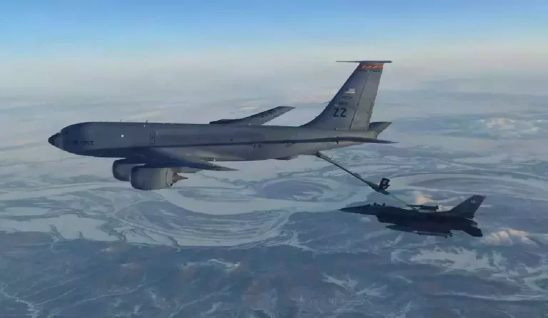 Air Force KC-135 Stratotanker refueling a fighter jet in mid-air over a snowy landscape.