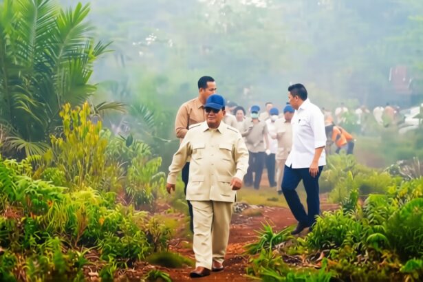 Group of officials walking along a muddy path through lush tropical plants, led by a man in a beige uniform and blue cap.