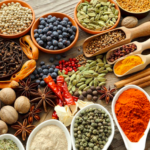 Assorted spices and spice blends arranged in bowls and scoops on a wooden table.