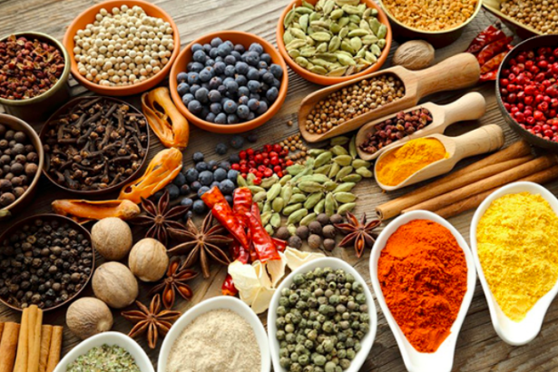 Assorted spices and spice blends arranged in bowls and scoops on a wooden table.