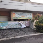 Front of a daycare center with banners across the gate, advertising Little Aresha and a daycare program Plus. A yellow caution tape runs along the fence.