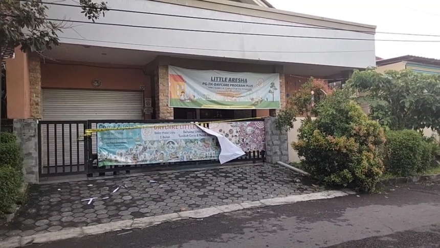 Front of a daycare center with banners across the gate, advertising Little Aresha and a daycare program Plus. A yellow caution tape runs along the fence.