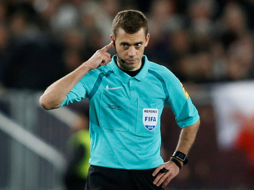 Coupe de la Ligue Final - Paris St Germain vs AS Monaco - Mabur.co Soccer referee in turquoise uniform with headset, touching his ear during a match on the field.