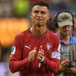 Cristiano Ronaldo in Portugal red kit clapping on the field with a camera crew in the background