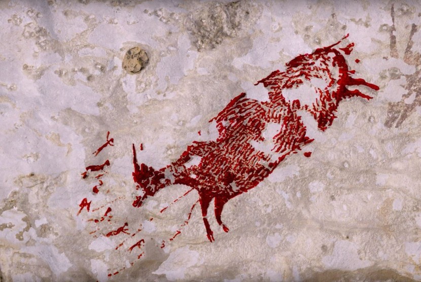 Red stencil of a dead animal spray-painted on a pale stone wall (graffiti)