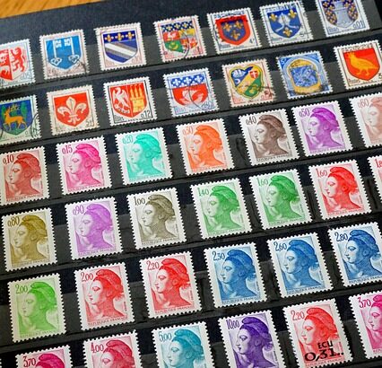 A sheet of assorted postage stamps arranged in diagonal rows, showing portraits, coats of arms, and crests in many colors on a dark background.