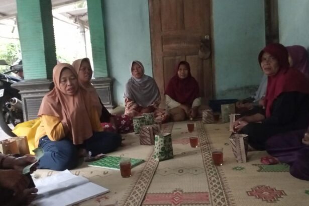 Group of women wearing hijabs sit cross-legged on a patterned mat in a circle, sharing tea and snacks in a doorway-adjacent room.