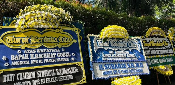 Three large flower-decorated condolence boards with blue and yellow motifs displayed outdoors.