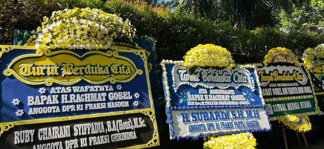 Three large flower-decorated condolence boards with blue and yellow motifs displayed outdoors.